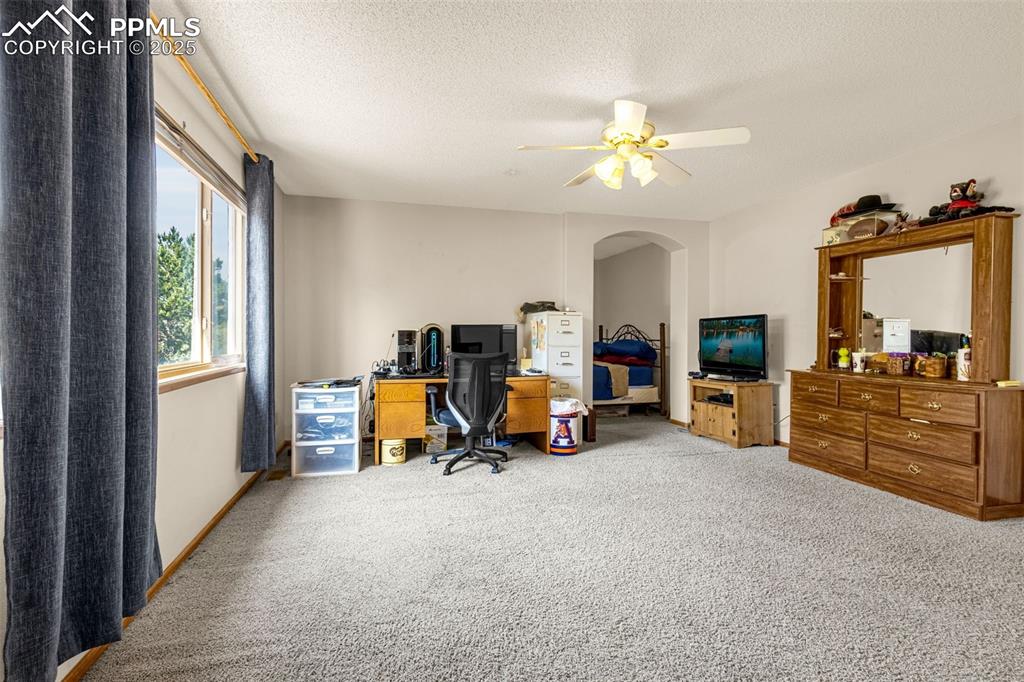 Image 11 of 33: Home office with carpet flooring, a textured ceiling, a ceiling fan, and ar