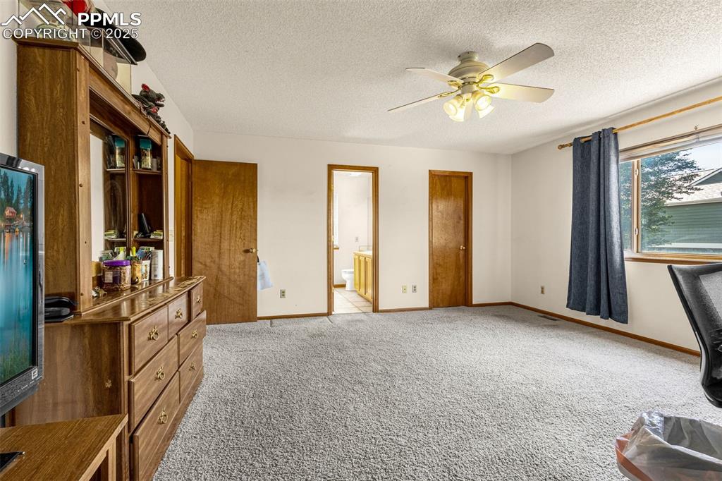 Image 12 of 33: Bedroom featuring carpet flooring, a textured ceiling, ensuite bath, and a 