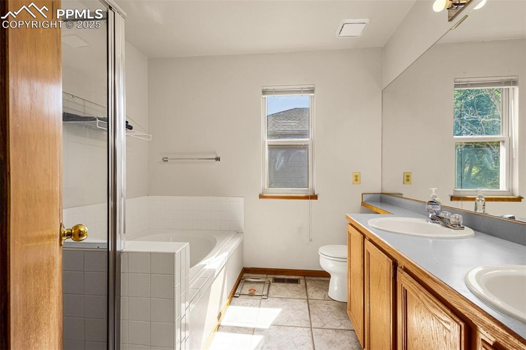 Image 13 of 33: Bathroom with a garden tub, double vanity, and a stall shower