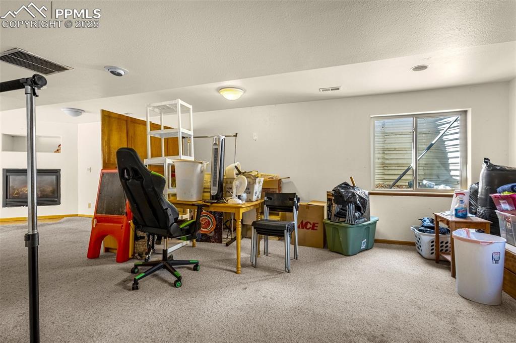 Image 19 of 33: Home office featuring carpet floors, a multi sided fireplace, and a texture