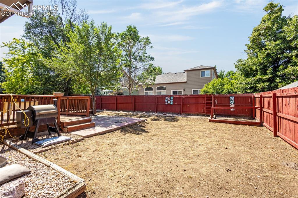 Image 25 of 33: Fenced backyard with a wooden deck