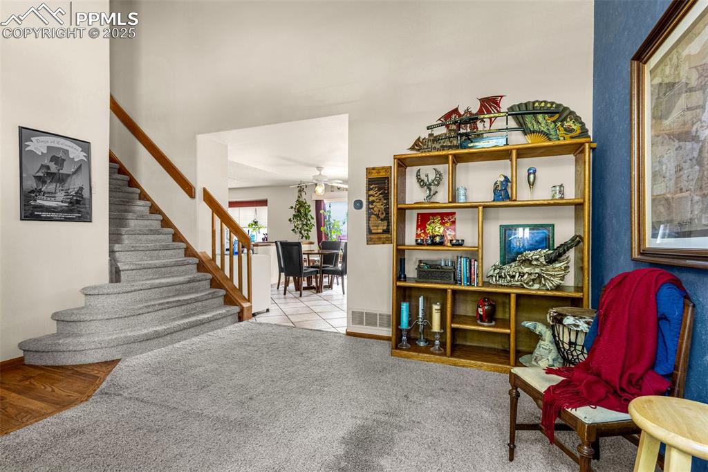 Image 4 of 33: Sitting room with stairs, ceiling fan, and carpet