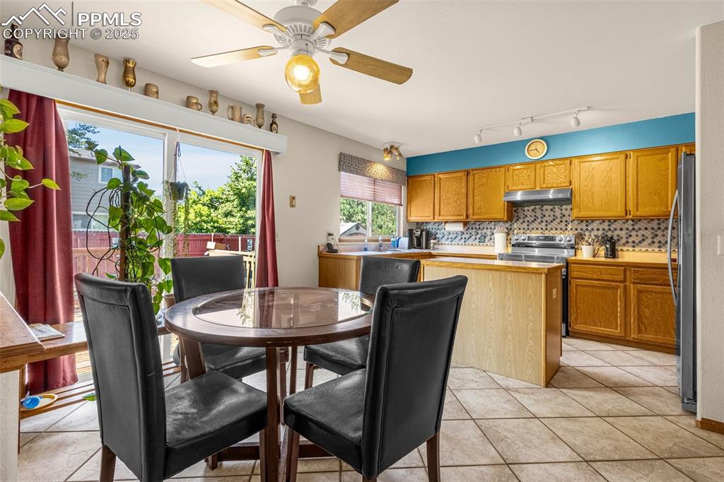 Image 7 of 33: Dining space featuring a ceiling fan, track lighting, and light tile patter