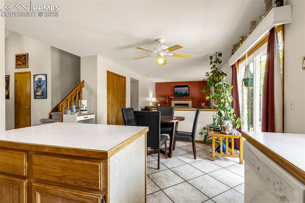 Image 9 of 33: Kitchen featuring dishwasher, ceiling fan, a fireplace, and light counterto