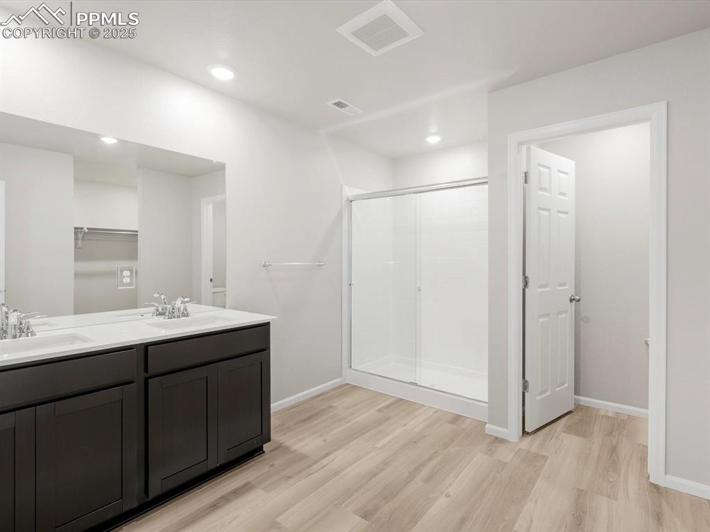 Image 6 of 15: Bathroom with a stall shower, double vanity, light wood-style floors, and r