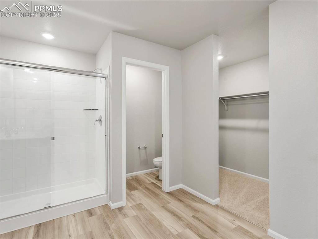 Image 7 of 15: Full bathroom featuring a stall shower, a walk in closet, light wood finish