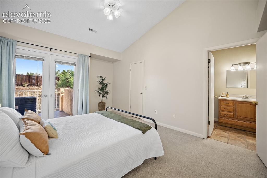 Image 17 of 42: Primary bedroom with view to private deck and primary bath