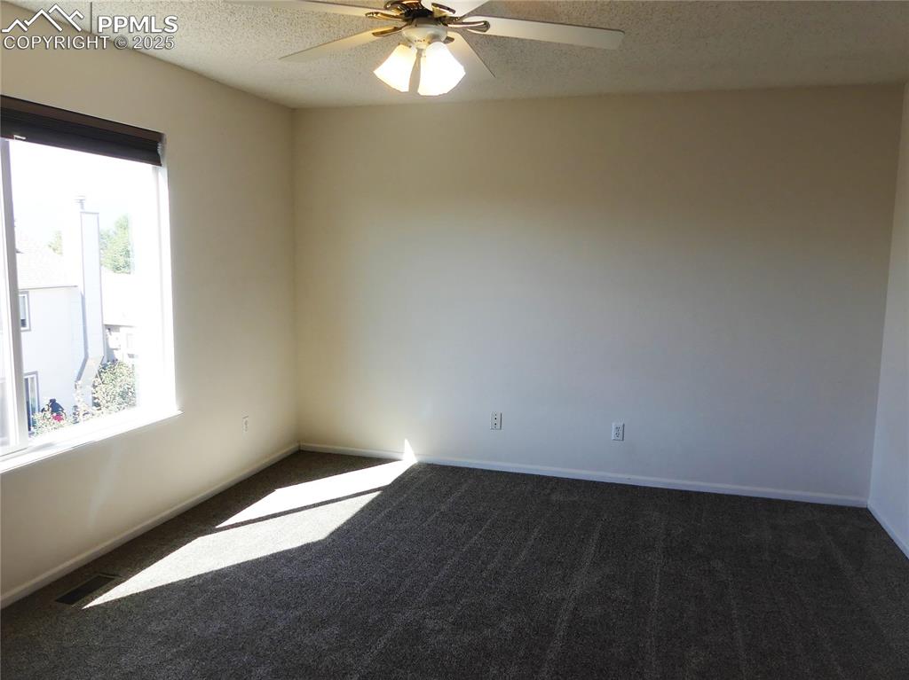 Image 33 of 42: Unfurnished room with dark colored carpet, a textured ceiling, and a ceilin