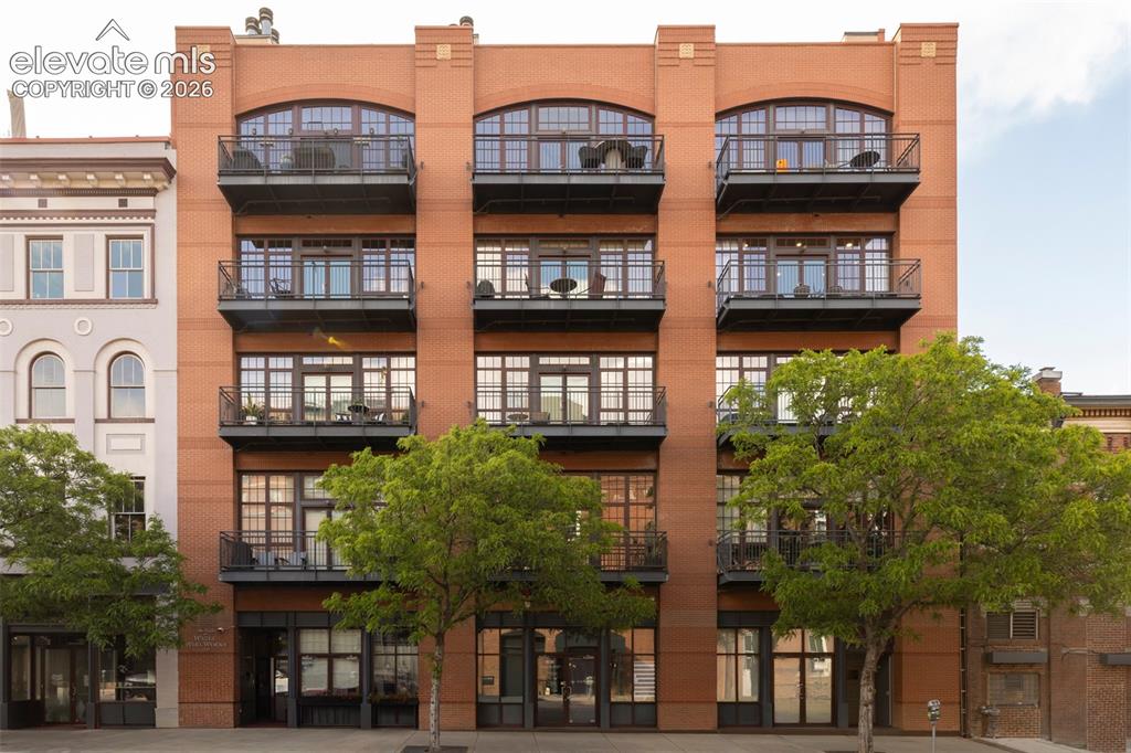 Image 1 of 33: Brick facade with arch-top windows, multiple private balconies, and ground-
