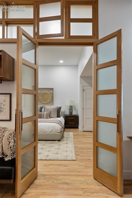 Image 13 of 33: Frosted glass French doors with wood frames, wood-finish flooring, and rece