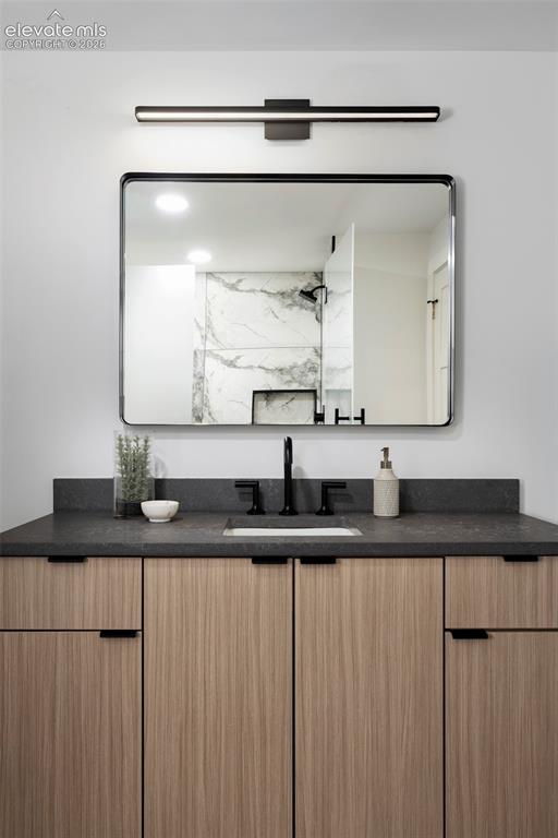 Image 16 of 33: Wood-finish vanity with a dark countertop, matte black faucet, and an integ