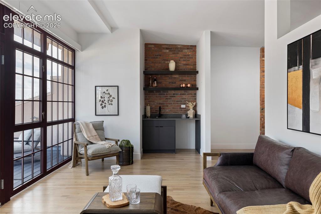 Image 18 of 33: Expansive glass panel doors, wood-finish flooring, exposed brick accent wal