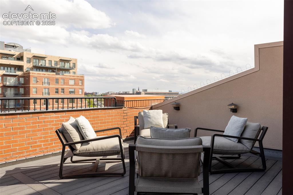 Image 22 of 33: Rooftop patio with composite decking, exposed brick wall, and wall-mounted