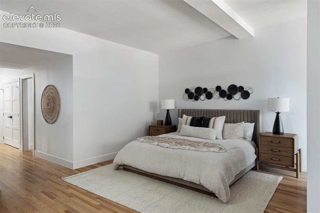 Image 25 of 33: Wood-finish flooring, white walls, and a visible ceiling beam