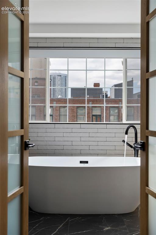 Image 27 of 33: Freestanding soaking tub with a floor-mounted faucet, black marble-look flo