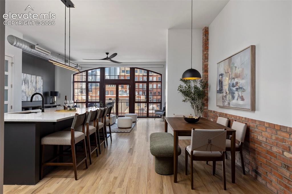 Image 4 of 33: Open-concept living space featuring wood-finish flooring, exposed brick acc