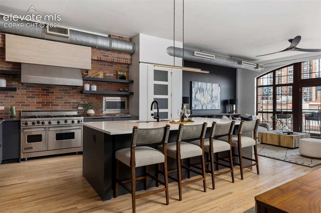 Image 5 of 33: Exposed brick wall, stainless steel range with matching hood, kitchen islan