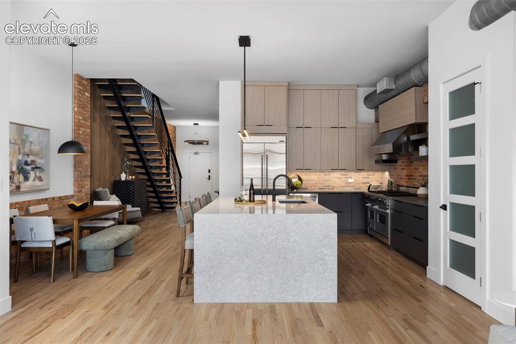 Image 6 of 33: Open-concept living space with wood-finish flooring, a contemporary kitchen