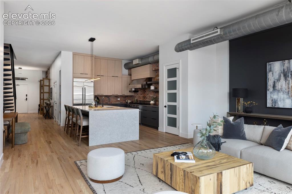 Image 8 of 33: Open-concept living area with light wood-finish flooring, a kitchen island,