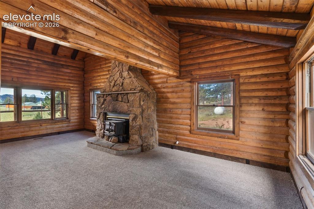 Image 3 of 32: Exposed log walls, wood beams and vaulted ceiling highlight the home