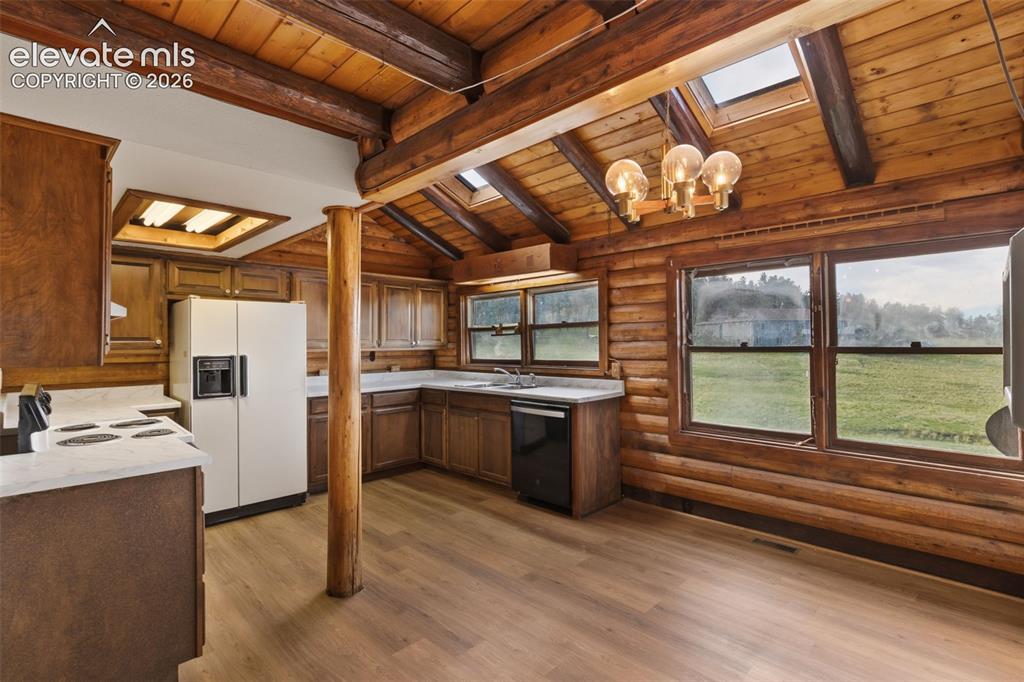Image 6 of 32: Open kitchen and dining area surrounded by the warmth of exposed log walls.