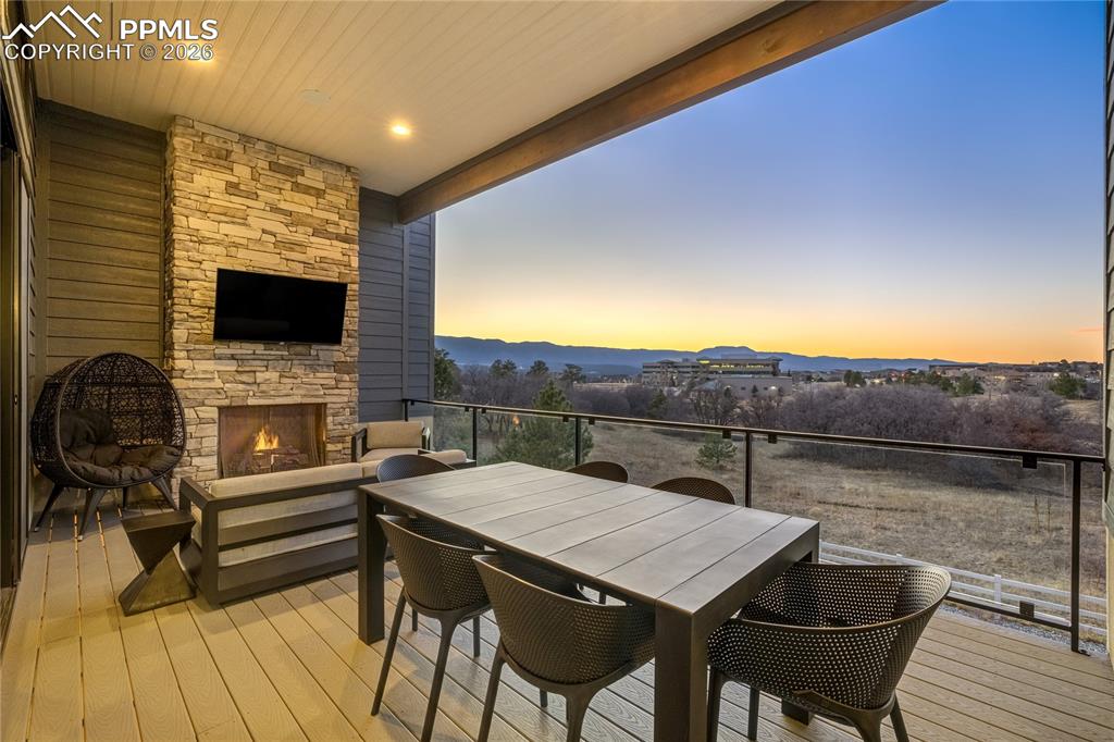 Image 14 of 50: Covered Trex deck with fireplace, designed for evenings under open skies. G