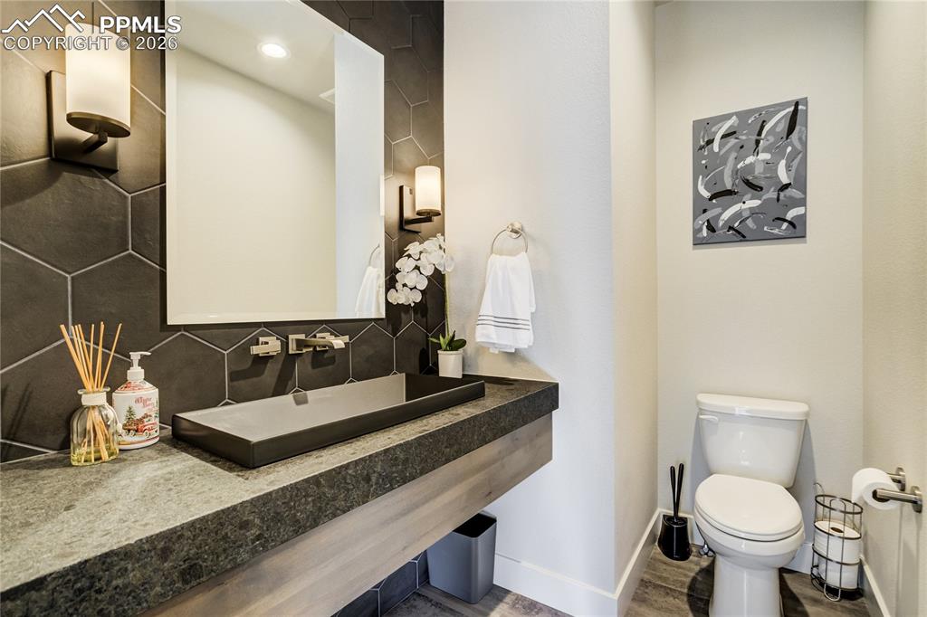 Image 24 of 50: Floating vanity with suede leathered granite and bold hex tile backdrop
A 