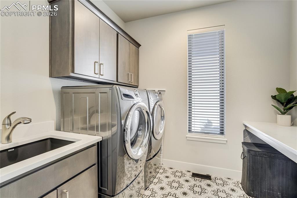 Image 25 of 50: Main level laundry with patterned tile flooring and quartz surfaces elevati