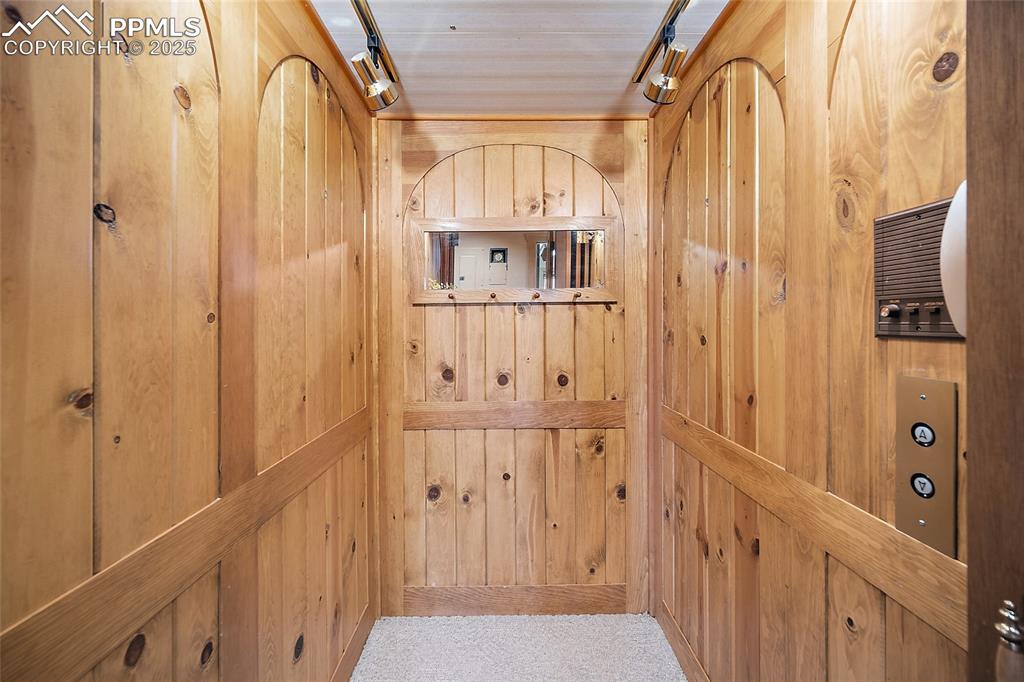 Image 12 of 31: Elevator featuring wooden walls and track lighting