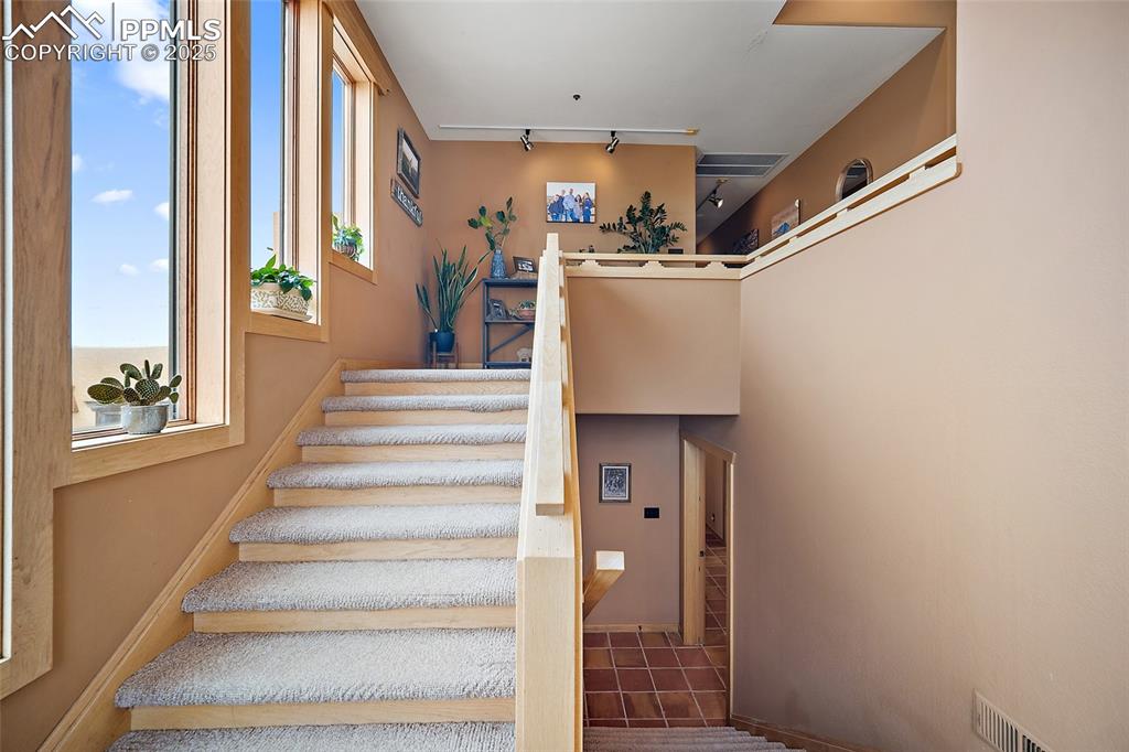 Image 14 of 31: Stairs with tile patterned floors and track lighting