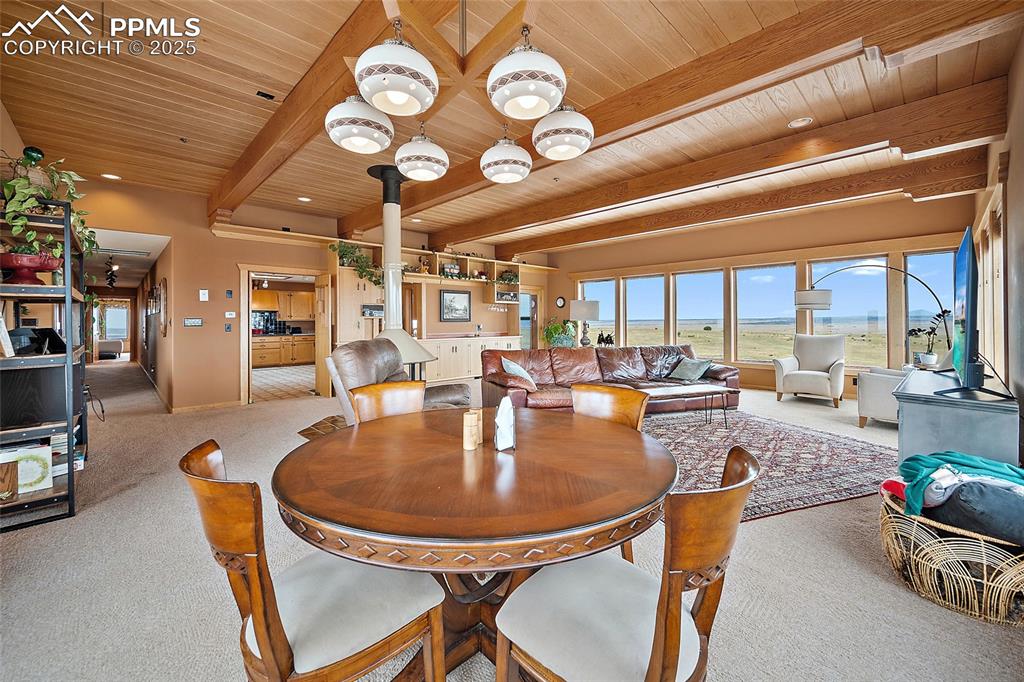 Image 17 of 31: Carpeted dining space with a wood ceiling with exposed beams and baseboards