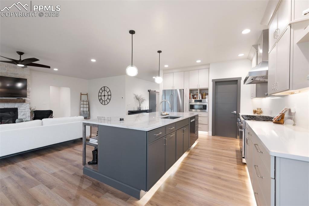 Image 11 of 42: Kitchen featuring an island with sink, hanging light fixtures, open floor p