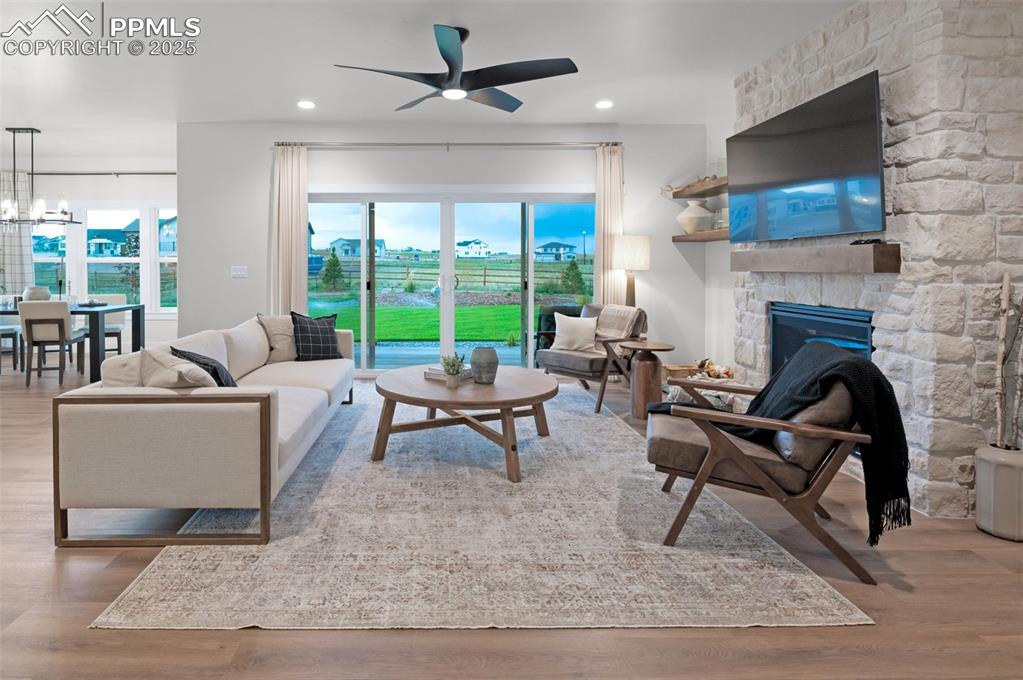 Image 17 of 42: Living room with light wood-style floors, a stone fireplace, healthy amount