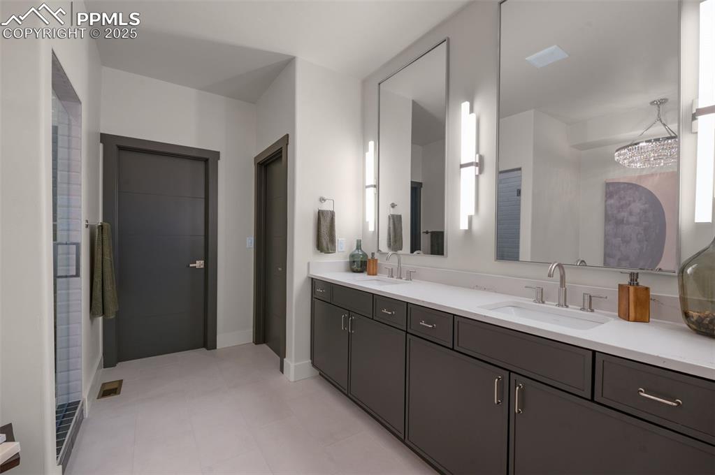 Image 19 of 42: Bathroom with double vanity, a chandelier, and light tile patterned floors