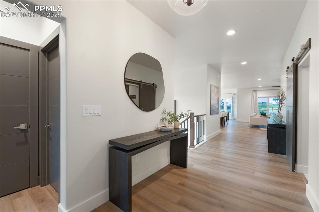 Image 2 of 42: Hallway with a barn door, light wood-style flooring, and recessed lighting
