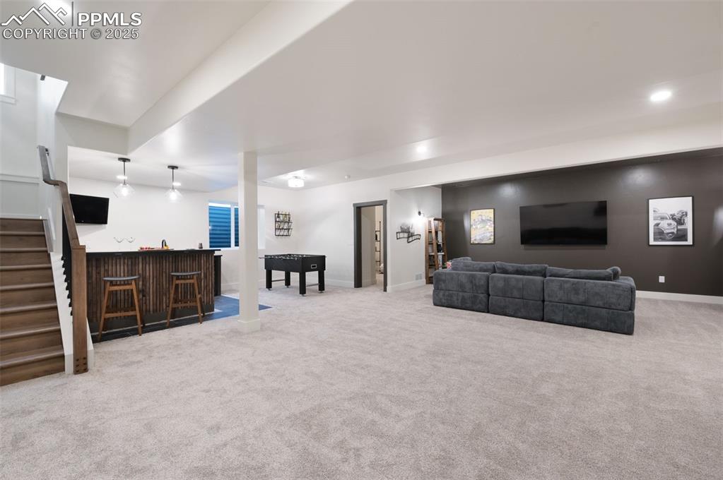 Image 24 of 42: Living room featuring bar area, light colored carpet, stairway, and recesse
