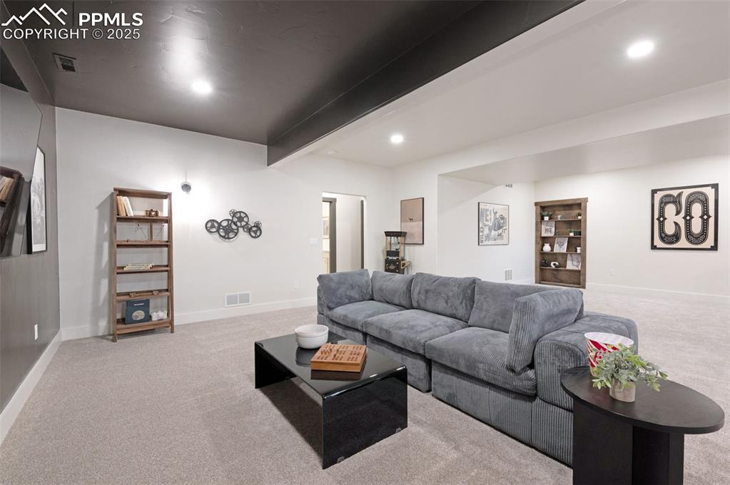 Image 27 of 42: Living room with beamed ceiling, light carpet, and recessed lighting