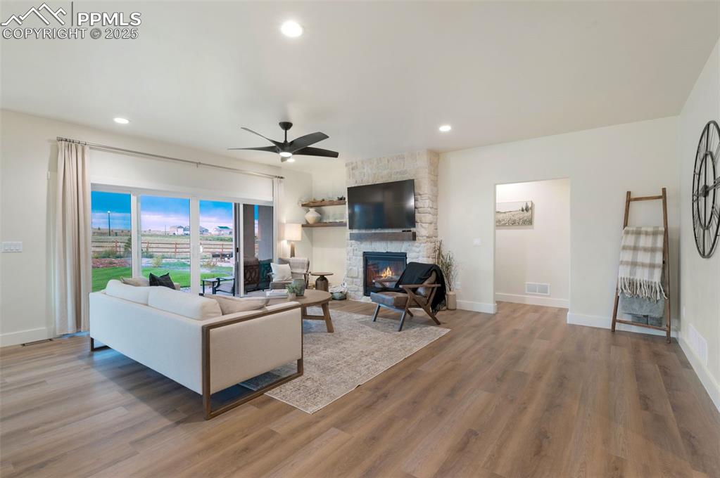 Image 4 of 42: Living area featuring a stone fireplace, a ceiling fan, recessed lighting,