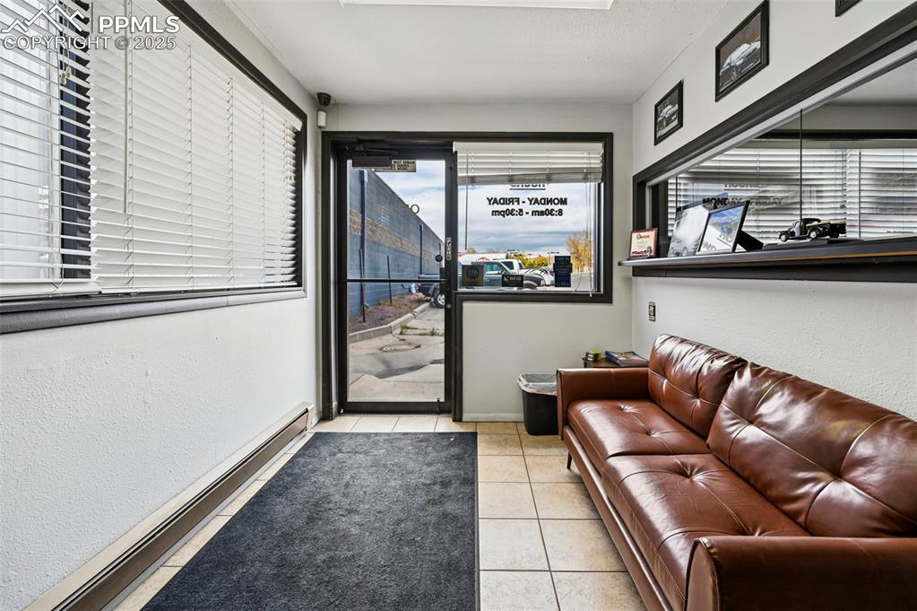 Image 2 of 13: Living area with baseboard heating, light tile patterned flooring, and a te