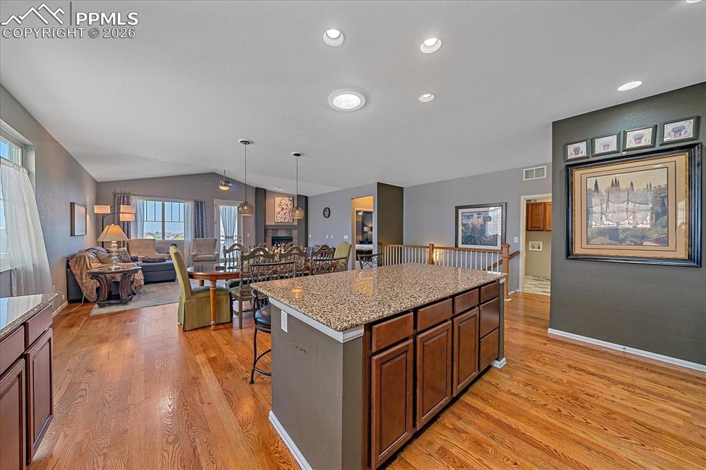 Image 13 of 47: Kitchen featuring a kitchen bar, a kitchen island, lofted ceiling, open flo