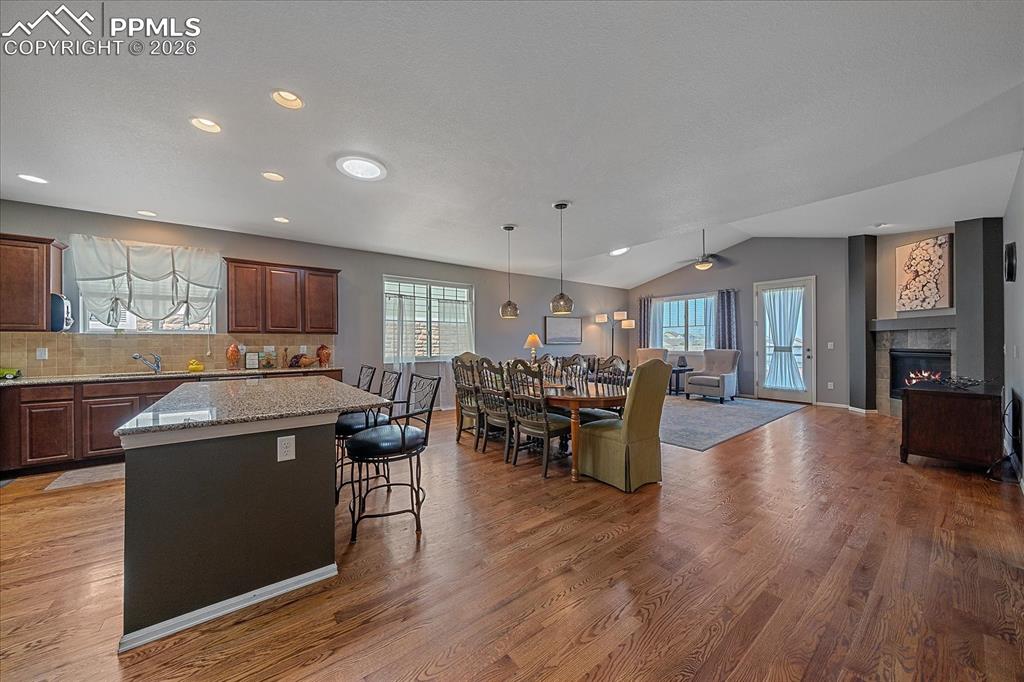 Image 14 of 47: Kitchen with a center island, a kitchen bar, tasteful backsplash, pendant l