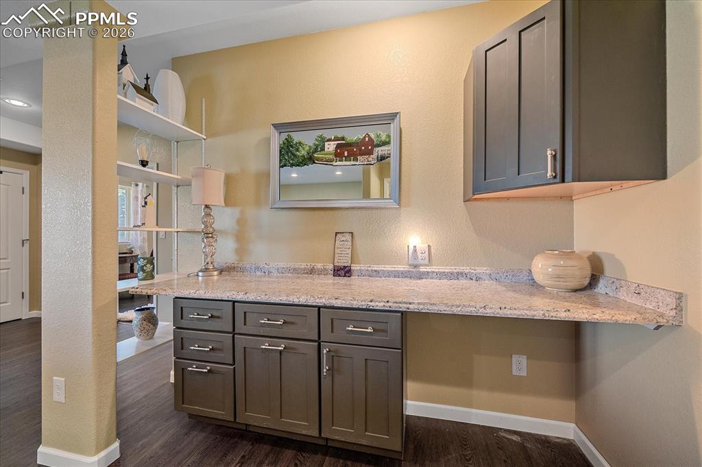 Image 28 of 47: Dry Bar area featuring light stone counters, gray cabinets, dark wood finis