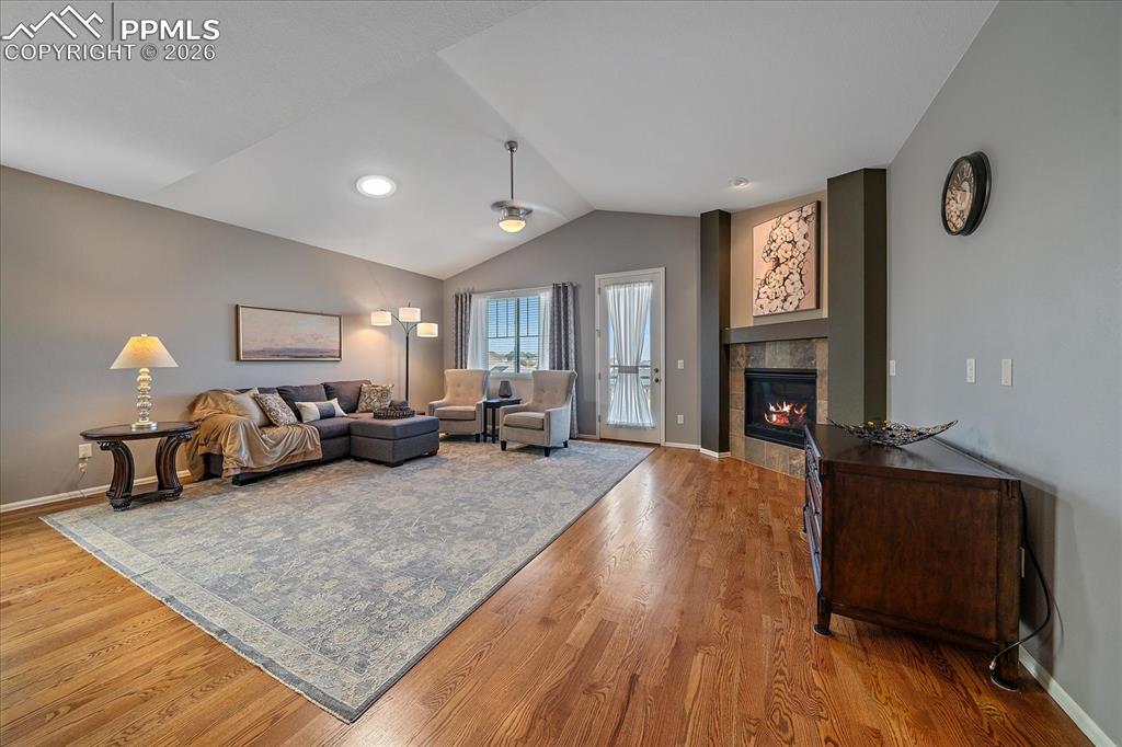 Image 4 of 47: Living room featuring vaulted ceiling, a tiled fireplace, and light wood-st