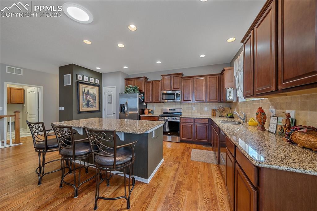 Image 9 of 47: Kitchen featuring backsplash, stainless steel appliances, a breakfast bar,