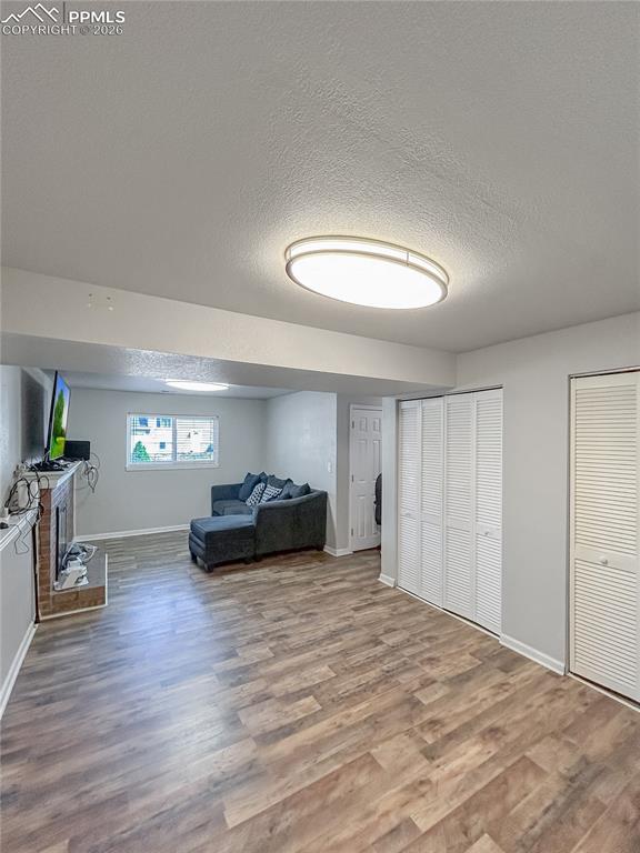 Image 18 of 28: Living Room; Spacious lower-level living area with wood-style flooring, neu