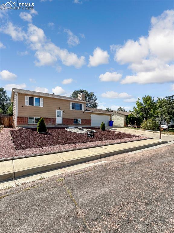 Image 2 of 28: Front of Home; Split-level home with tan siding, brick accents, and an atta