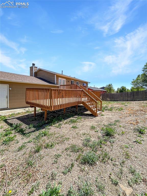 Image 25 of 28: Back-yard; Large fenced backyard with open space and a raised wooden deck.