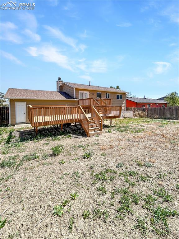 Image 26 of 28: Back-yard; Large fenced backyard with open space and a raised wooden deck.