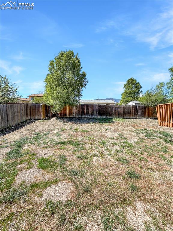 Image 28 of 28: Back-yard; Large fenced backyard with open space and a raised wooden deck.