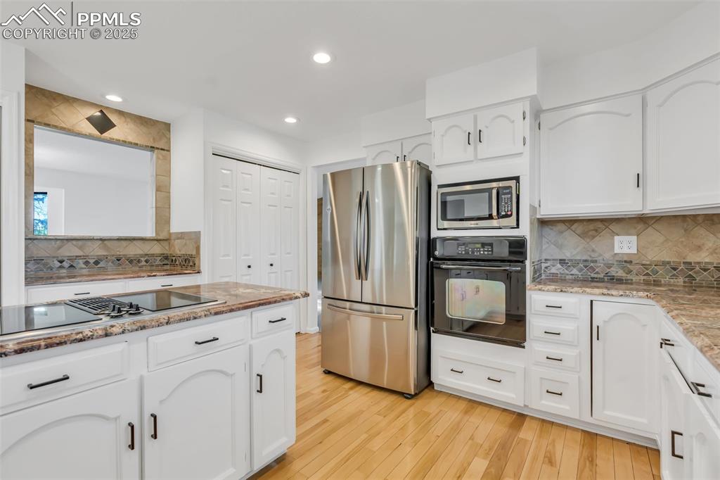 Image 16 of 46: Kitchen with appliances with stainless steel finishes, light wood-type floo